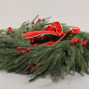 Couronne de Noël avec aiguilles de pin, baies rouges et nœud en velours sur fond gris