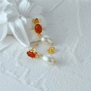 Detailed macro view of S925 silver earring with red gemstone and white teardrop pearl