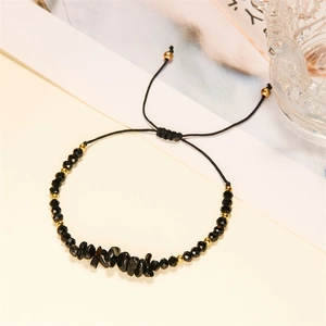 Detail eines verstellbaren handgemachten schwarzen Steinarmbands mit Goldperlen und Kristallen