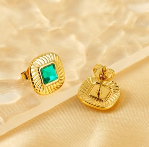 Detail of square gold stud earrings with emerald zircon and radial relief texture