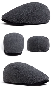 Detail view of grey herringbone wool cap with black brim and metal back buckle