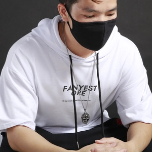 Close-up of retro silver skull pendant on a metal chain worn by a model in streetwear style