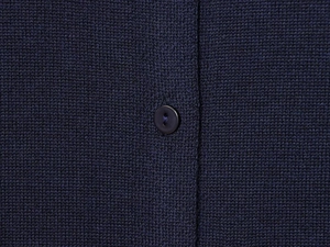 Detailed macro view of the navy blue knit cardigan fabric and matching round button