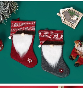 Close-up of red and grey knitted Christmas stockings with gnome Santa design on green background