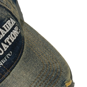 Dettaglio del berretto in denim invecchiato con ricamo bianco 3D e texture vintage wash