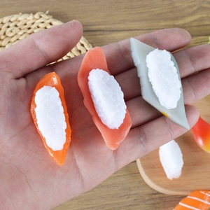 Realistic PVC salmon and tuna sushi food models held by hand on a wooden table