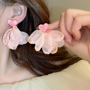 Close-up of pink mesh flower tassel earrings with heart-shaped stud on a model