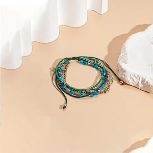 Detail van meerlagige glaskraal armband met verstelbaar koord en gouden accenten
