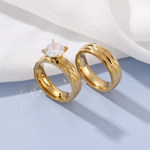 Matching gold titanium steel couple rings with diamond-cut texture and single stone setting