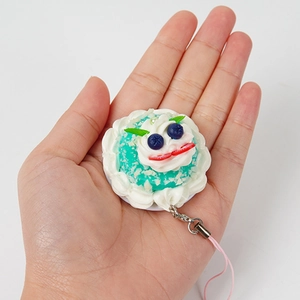 Miniature mint green dessert cake keychain with cream and berry toppings held in hand