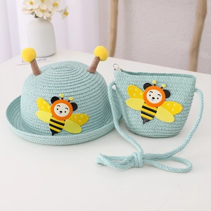 Close-up of mint green woven straw hat and matching crossbody bag with cute bee patches