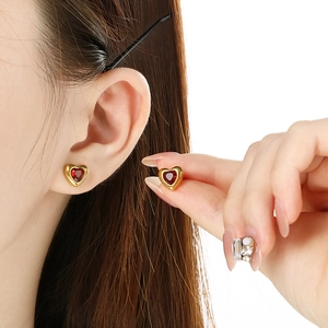 Golden heart earrings with red gemstones shown on a model for a vintage French look