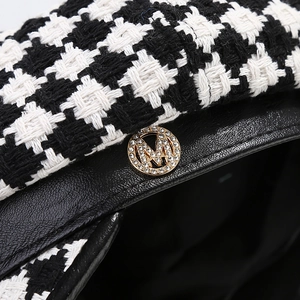 Detail of checkered tweed octagonal hat featuring a crystal-encrusted gold M logo