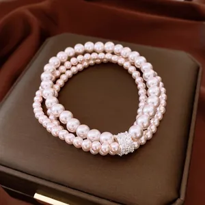 Bracelet multicouche en perles avec charmes en zircon sur présentoir en cuir marron