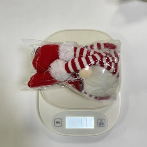 Close-up of a Christmas gnome plush ornament weighing 47.1g on a digital scale