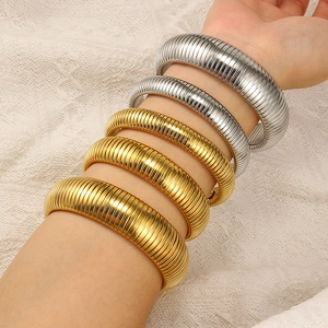 Detail of layered gold and silver snake bone bracelets on model with lace background