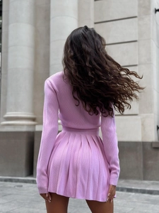 Completo in maglia rosa con top a maniche lunghe e gonna a pieghe su una modella