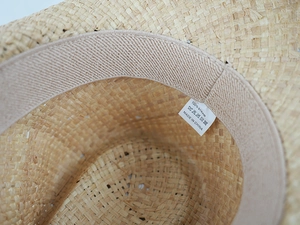 Detailed interior of woven straw hat featuring sweatband and 100% straw material label