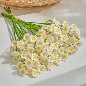 Top view of white faux daisy bouquet with yellow centers on a clean white background