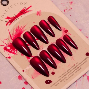 Glossy burgundy stiletto press-on nails with metallic finish on display card