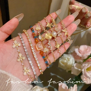 Close-up of multiple gold and silver fashion bracelets with butterfly and pearl charms