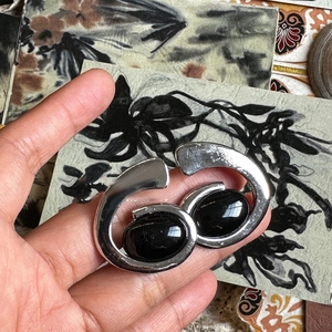 Detail of silver polished metal choker with asymmetric resin oval pendant and artistic design