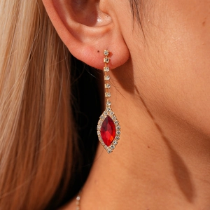 Detail of red marquise crystal pendant earrings with gold tassels on a model