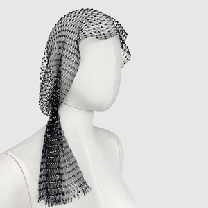 Detail of black fishnet headpiece with shimmering rhinestones on a white mannequin