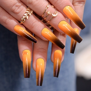 Detail of long coffin nails featuring orange to dark brown gradient with high-gloss finish