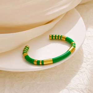 Detail of green enamel and gold plated stainless steel striped cuff bracelet