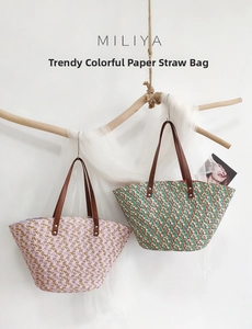 Detail of colorful woven paper straw tote bags with brown leather handles on wooden branch
