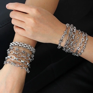 Stack of silver-tone stainless steel chain bracelets shown on a model wrist with dark background