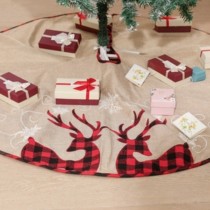 Close-up of linen Christmas tree skirt with reindeer and red plaid trim under a decorated tree