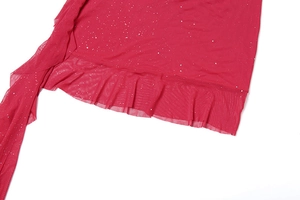 Detail eines roten Netzkleides mit glitzerndem Silberstaub und Rüschensaum