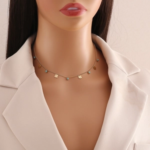 Gold stainless steel necklace with clover charms and turquoise beads on a model