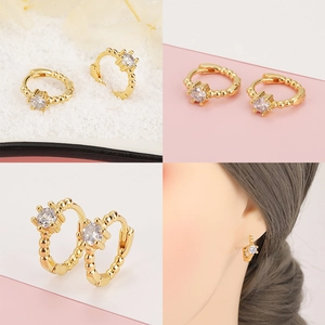 Detalle de pendientes chapados en oro 18K con circón blanco y borde perlado, vista puesta