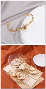 Detail of hammer-textured gold C-shape bangles with colorful inlaid sunburst stones