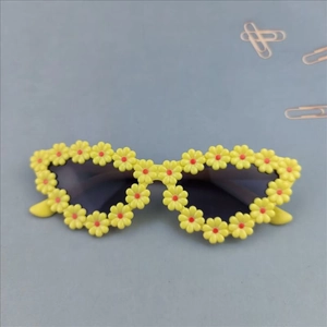 Detailed close-up of yellow daisy flower frame sunglasses with dark grey lenses for kids