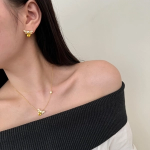 Close-up of golden bee jewelry set with yellow pear-shaped stones worn by a model