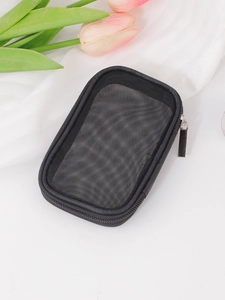 Close-up of black mesh travel organizer bag with metal zipper on a white textured background