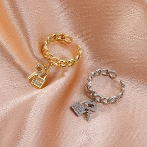 Detail of gold and silver chain rings with micro-pave zircon lock and key pendants