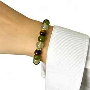 Detail of multi-color gemstone beads with gold spacers worn on a wrist in a bright setting