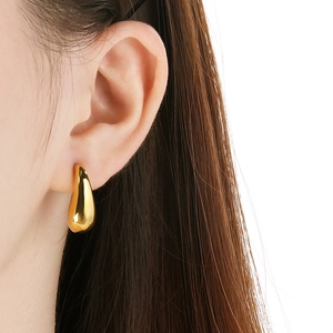 Close-up of a polished 18k gold waterdrop earring on model with minimalist design