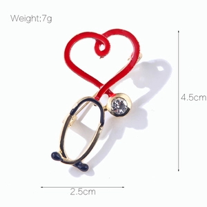 Détail de la broche stéthoscope cœur en émail rouge avec un accent cristallin