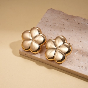 Macro view of gold flower earrings with metallic mirror finish on textured stone