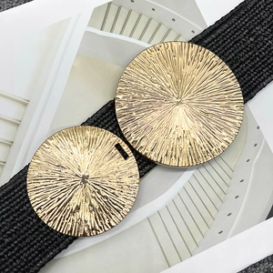 Close-up of black woven elastic belt featuring two large ornate gold metal circular buckles