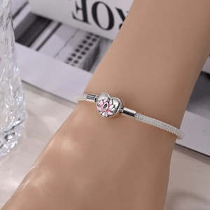 Silver mesh bracelet featuring a heart-shaped clasp with a pink lotus detail on wrist