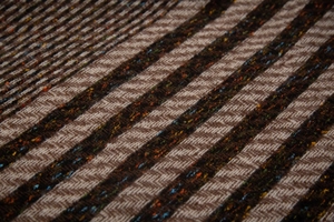 Macro shot of herringbone weave scarf fabric with brown beige stripes and colorful flecks