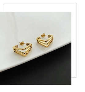 Macro detail of triple-layered golden geometric square earrings with polished metallic finish