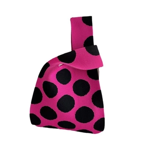 Detail of fuchsia knitted tote bag with black polka dots and single top handle texture